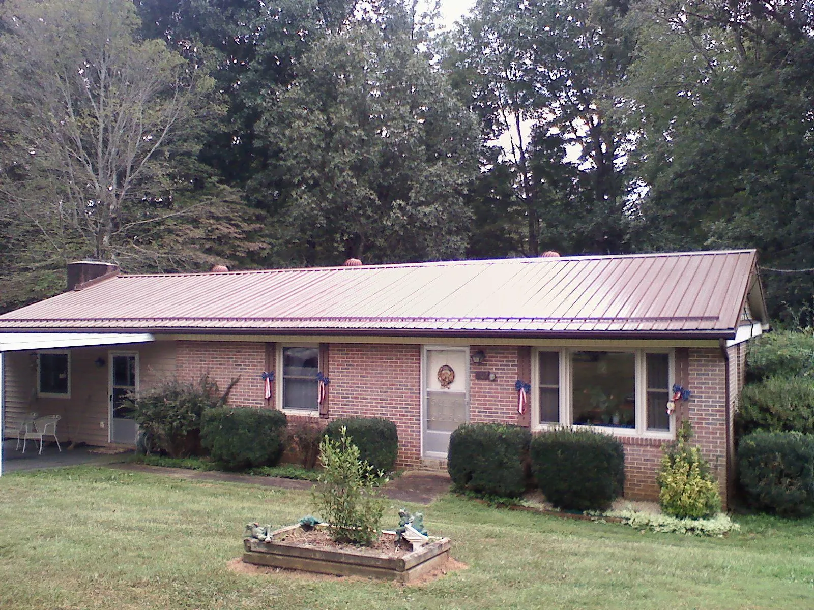 Bronze metal roof on a brick ranch home with a carport in Forest
